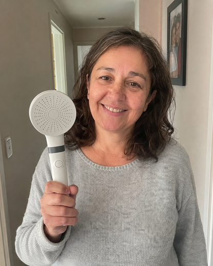 Clienta de Equiora sosteniendo su Ducha Filtrada en su casa